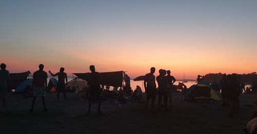 Silhouette people on beach against sky during sunset