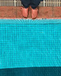 Low section of man standing by swimming pool