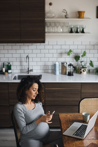 Female freelancer using smart phone while working at home