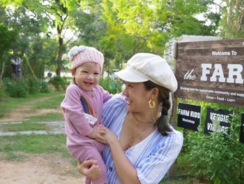 Smiling mother carrying baby on field