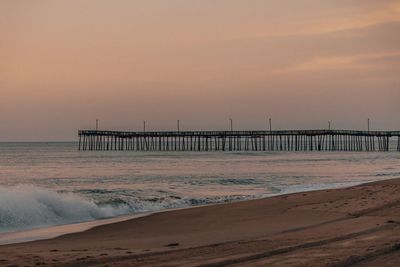 Pier over sea against sky during sunset