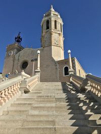 Low angle view of cross amidst buildings against sky