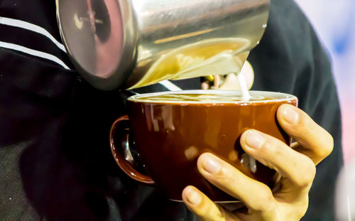 Close-up of hand pouring coffee in cup