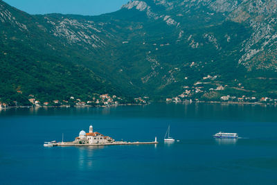 Sailboats in sea against mountains