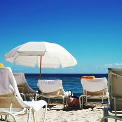 Deck chairs on beach against clear blue sky