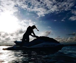 Silhouette men on boat in sea against sky