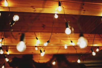 Low angle view of illuminated string lights hanging on ceiling