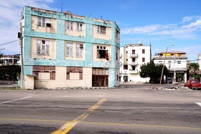 Road by buildings against sky in city