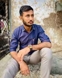 Young man sitting on wall