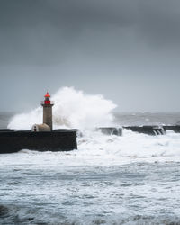 Lighthouse by sea against sky