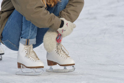 Low section of woman ice-skating on ice rink during winter