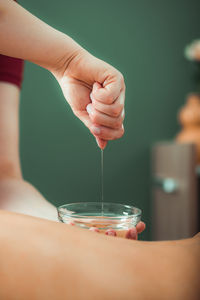 Massage oil. therapist pouring aromatic massage oil onto womans back