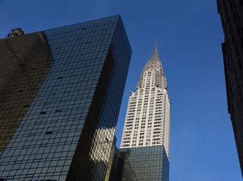 Low angle view of skyscrapers against blue sky