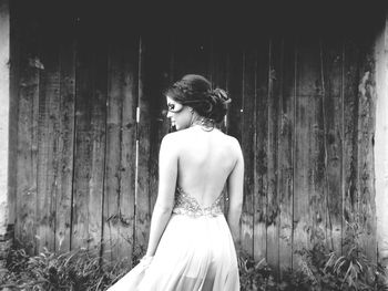 Rear view of young woman wearing backless dress standing by house