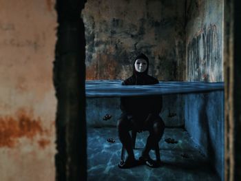 Full length portrait of woman sitting in abandoned building