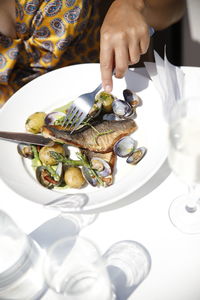 Midsection of man holding fish in plate on table