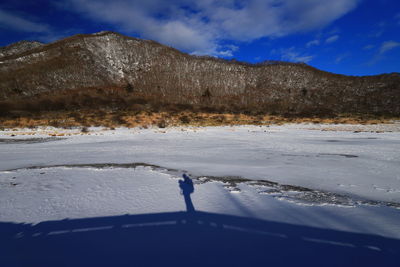 Person walking on snow covered land against sky