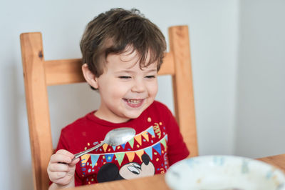 A boy is having fun at the breakfast table eating oatmeal