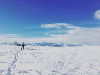 Rear view of person skiing with dog on snow against sky