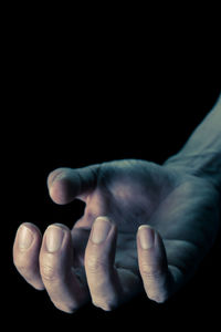 Close-up of hand over black background