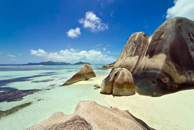 Rocks on beach against blue sky