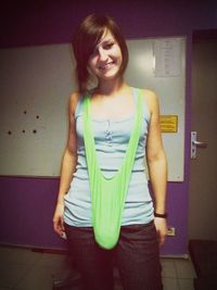 Portrait of a smiling young woman standing against wall