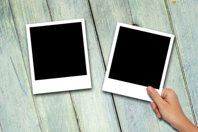 Close-up of person holding photographs on table 