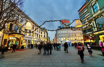 People walking on street amidst buildings in city