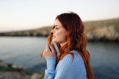 Portrait of beautiful woman standing against sky during sunset