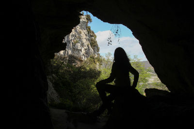Full length of silhouette woman sitting in cave