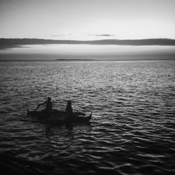 Silhouette men sailing on boat in sea