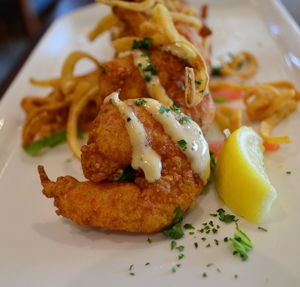 Close-up of fried shrimps with lemon served in plate at restaurant