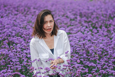 Young woman with pink flowers on field