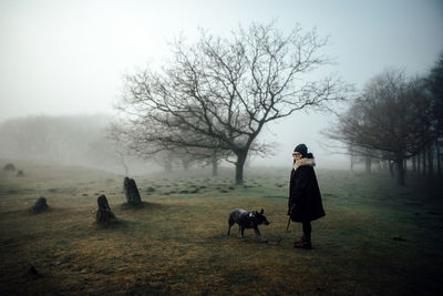 Side view of woman with dog on grassy hazy landscape