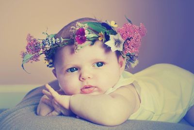 Close-up of cute toddler wearing flower wreath lying on bed at home