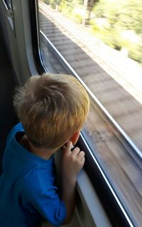 High angle view of boy looking through window in train