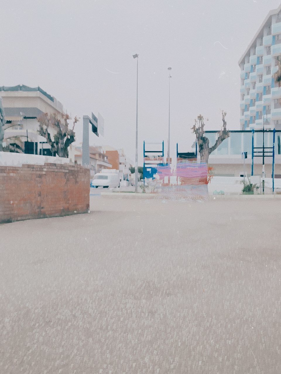 EMPTY ROAD AMIDST BUILDINGS AGAINST SKY