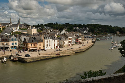 Boats in river by townscape against sky