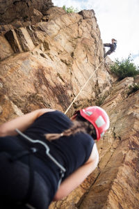 Low section of man holding cliff against sky
