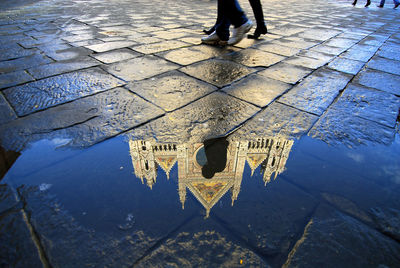 Low section of people walking on street by puddle