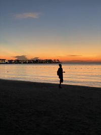 Silhouette man standing on beach against sky during sunset