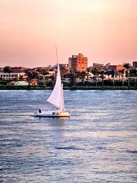 Sailboat sailing in sea against sky during sunset