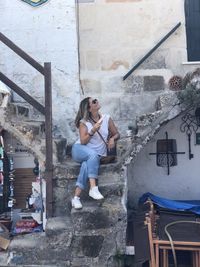 Woman sitting on staircase against building