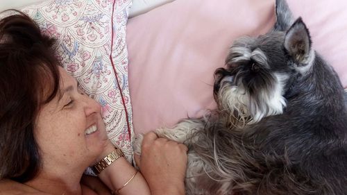 High angle view of woman with dog lying on bed at home