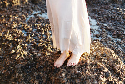 Feet of woman in dress standing on rock