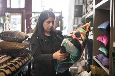 Side view of mature female customer looking at cushion in store