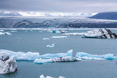 High angle view of icebergs in lake against cloudy sky