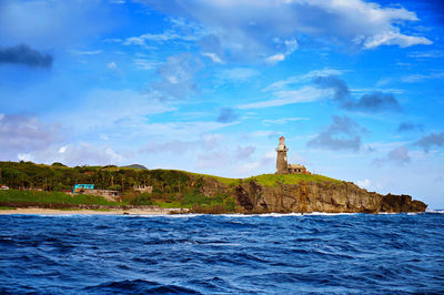 Lighthouse by sea against sky