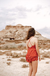 Full length rear view of woman standing on field against sky