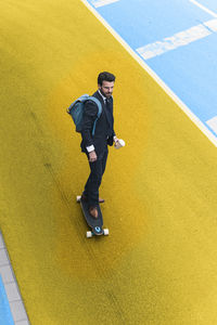 High angle view of man standing with yellow umbrella